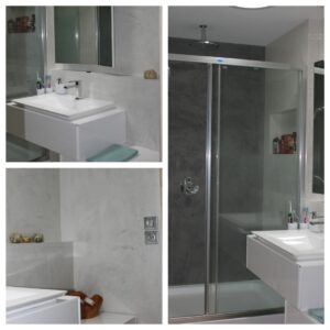 Salle de bain moderne avec douche vitrée, lavabo blanc flottant et murs texturés gris clair et anthracite. Prise électrique visible.