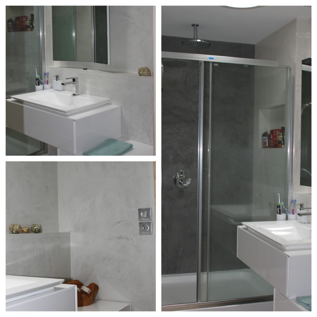 Salle de bain moderne avec douche vitrée, lavabo blanc flottant et murs texturés gris clair et anthracite. Prise électrique visible.